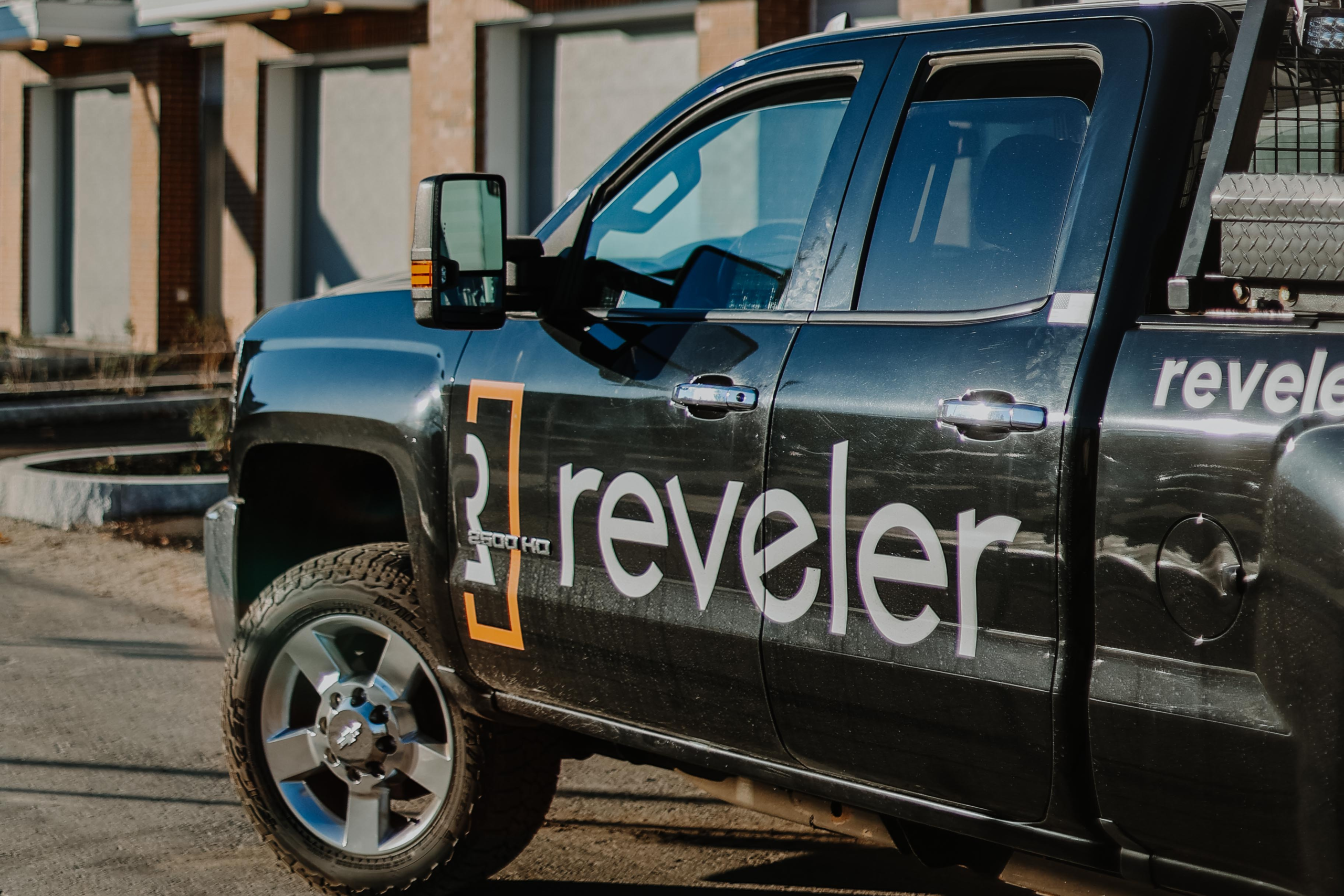 Photo of a group of three men sitting around a table discussing building plans.
